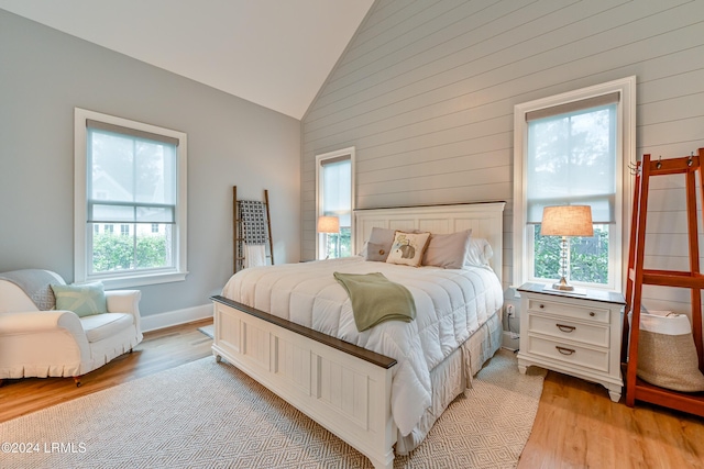 bedroom featuring multiple windows, light hardwood / wood-style flooring, and high vaulted ceiling