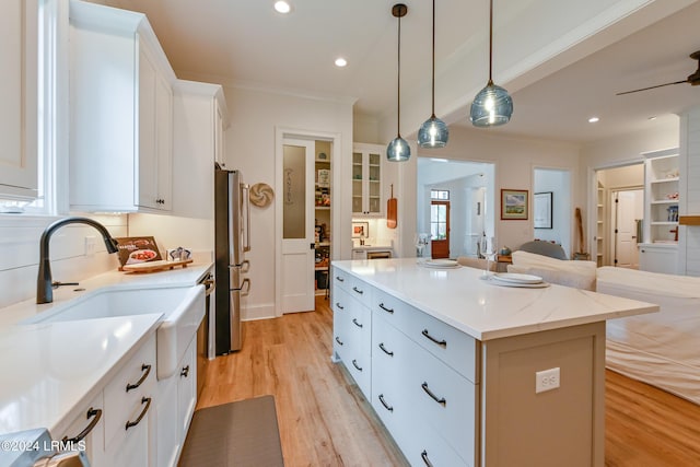 kitchen featuring a kitchen island, decorative light fixtures, white cabinetry, stainless steel fridge, and light hardwood / wood-style floors