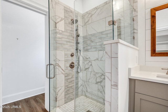 bathroom with wood-type flooring, a shower with door, and vanity