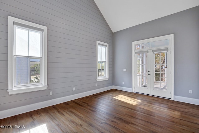 empty room with dark wood-type flooring, high vaulted ceiling, and french doors