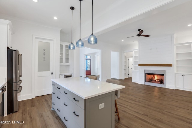 kitchen with white cabinetry, a center island, hanging light fixtures, and stainless steel refrigerator