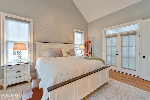 bedroom with french doors, lofted ceiling, and light hardwood / wood-style flooring