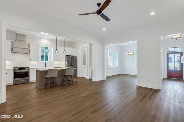 kitchen with custom exhaust hood, appliances with stainless steel finishes, a center island, and decorative light fixtures