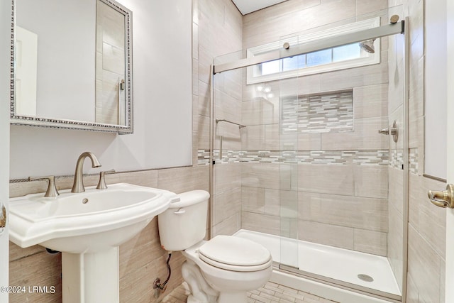 bathroom featuring toilet, tile walls, and a shower with shower door