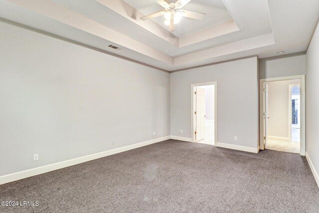 unfurnished bedroom featuring connected bathroom, a tray ceiling, carpet floors, and ceiling fan