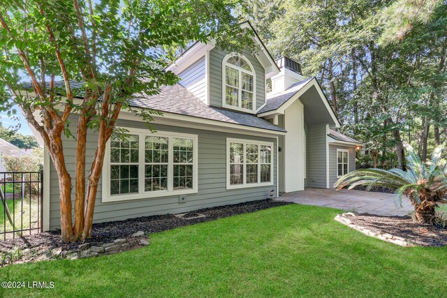 rear view of property featuring a lawn and a patio area