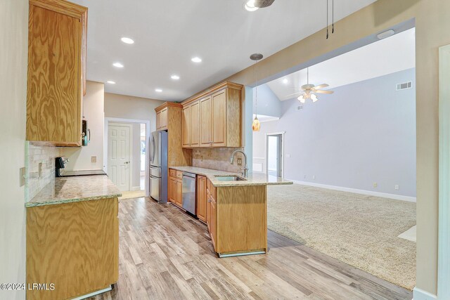 kitchen with appliances with stainless steel finishes, tasteful backsplash, sink, light stone counters, and kitchen peninsula