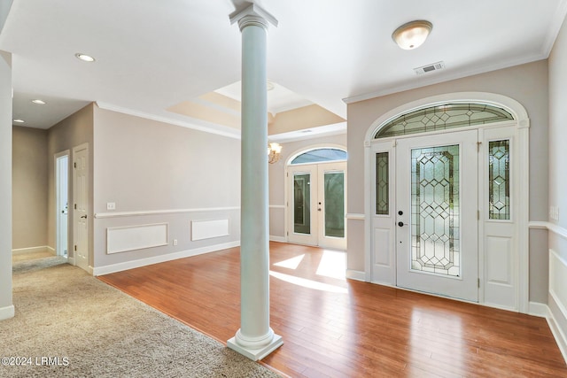 foyer with decorative columns, crown molding, hardwood / wood-style flooring, and a notable chandelier