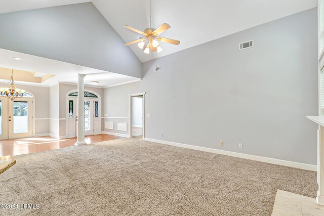 unfurnished living room featuring french doors, decorative columns, high vaulted ceiling, light colored carpet, and ceiling fan with notable chandelier