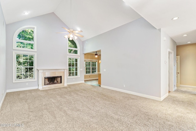 unfurnished living room featuring ceiling fan, light colored carpet, a tiled fireplace, and high vaulted ceiling