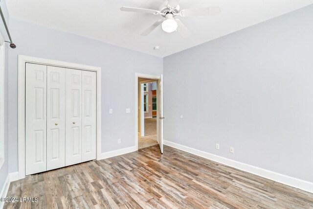 unfurnished bedroom with ceiling fan, a closet, and light hardwood / wood-style flooring