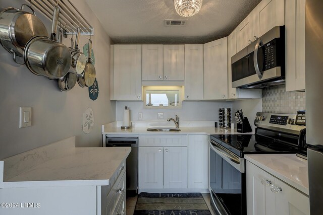 kitchen with stainless steel appliances, white cabinetry, sink, and a textured ceiling