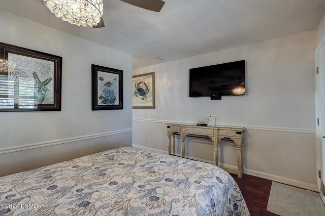 bedroom featuring dark hardwood / wood-style floors and ceiling fan with notable chandelier