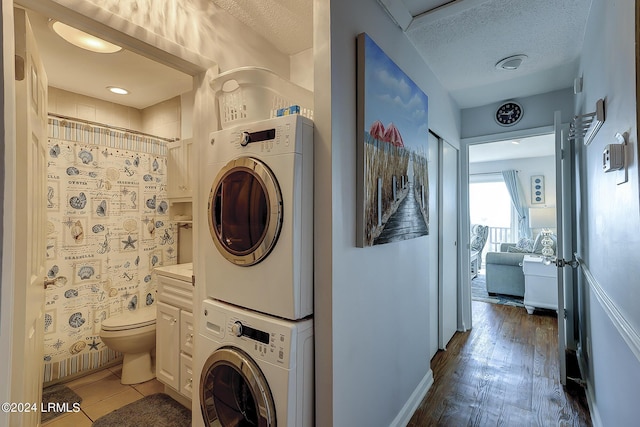 laundry room with dark hardwood / wood-style flooring, a textured ceiling, and stacked washer / dryer