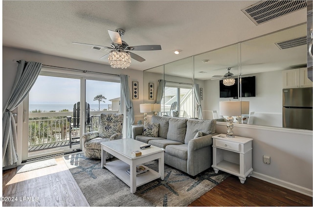 living room with a water view, dark wood-type flooring, a textured ceiling, and a wealth of natural light