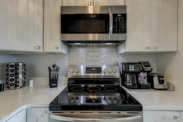 kitchen with white cabinetry, appliances with stainless steel finishes, and light stone counters