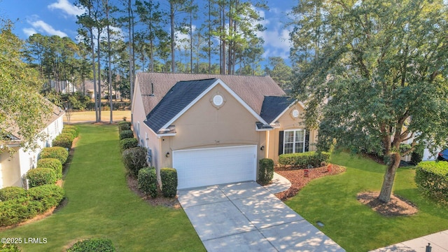 traditional-style home with a front lawn, driveway, an attached garage, and stucco siding