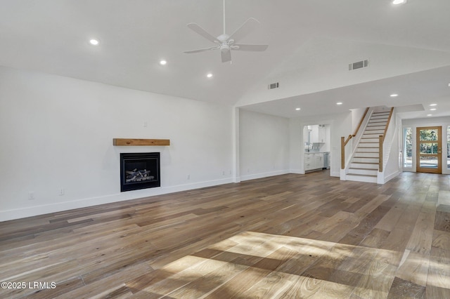 unfurnished living room with visible vents, baseboards, a fireplace, stairs, and wood-type flooring