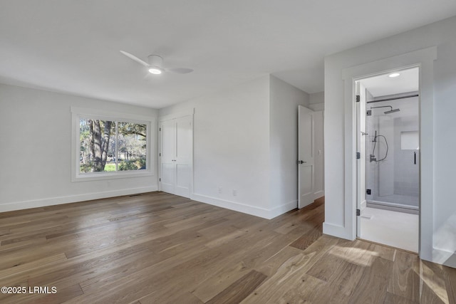 unfurnished bedroom featuring baseboards, a ceiling fan, wood finished floors, and ensuite bathroom