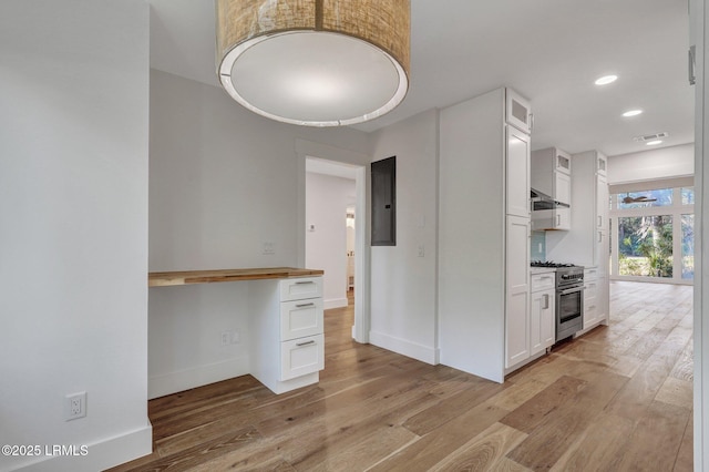 kitchen featuring glass insert cabinets, white cabinets, light wood-style floors, and high end stainless steel range oven