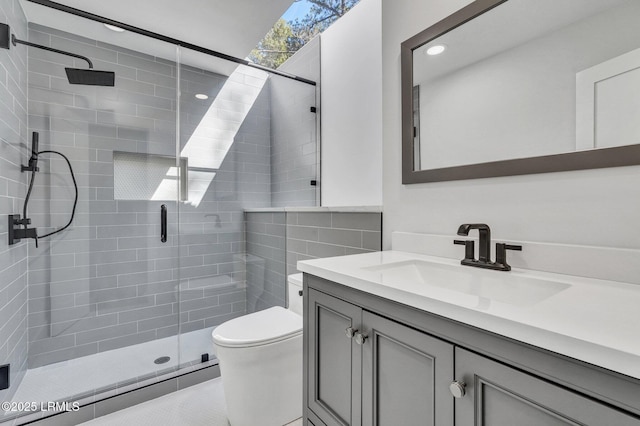 bathroom featuring a shower stall, toilet, and vanity