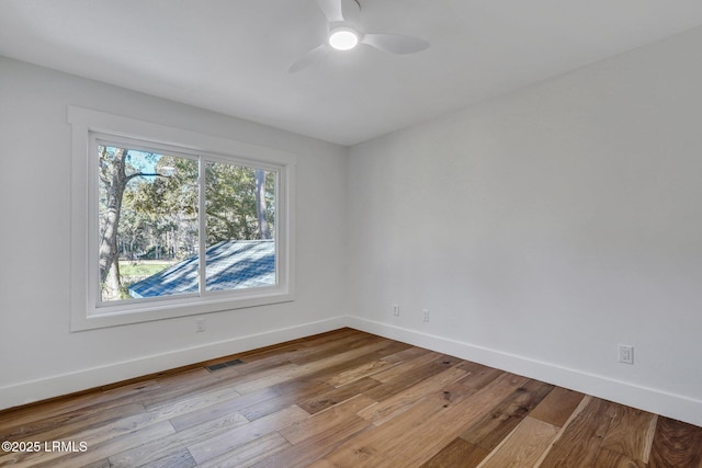 empty room featuring hardwood / wood-style floors, baseboards, visible vents, and ceiling fan