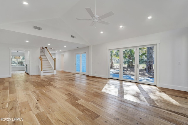 unfurnished living room with light wood finished floors, visible vents, stairway, and high vaulted ceiling