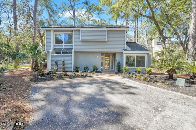 view of front of house with aphalt driveway, roof with shingles, and stucco siding