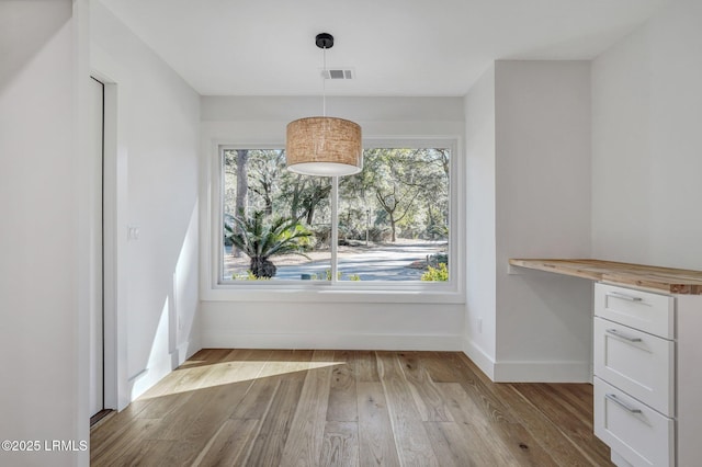 unfurnished dining area featuring visible vents, baseboards, and wood finished floors