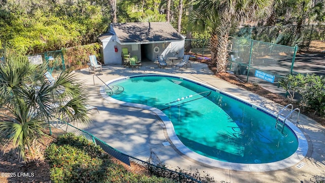 community pool with a patio, an outbuilding, and fence