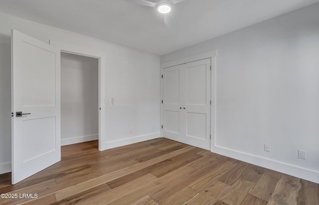 unfurnished bedroom featuring a ceiling fan, light wood-style floors, baseboards, and a closet