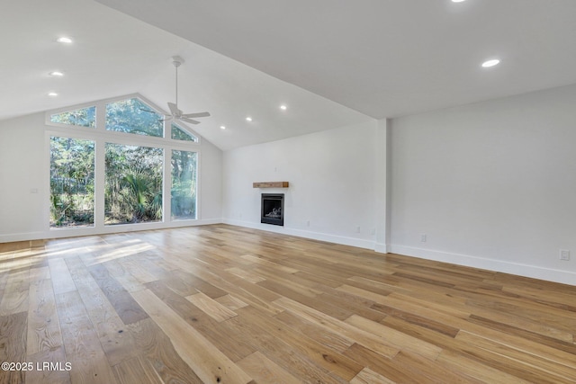 unfurnished living room featuring baseboards, a fireplace, ceiling fan, vaulted ceiling, and light wood-type flooring