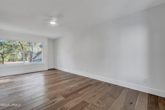 empty room with a ceiling fan, wood finished floors, and baseboards