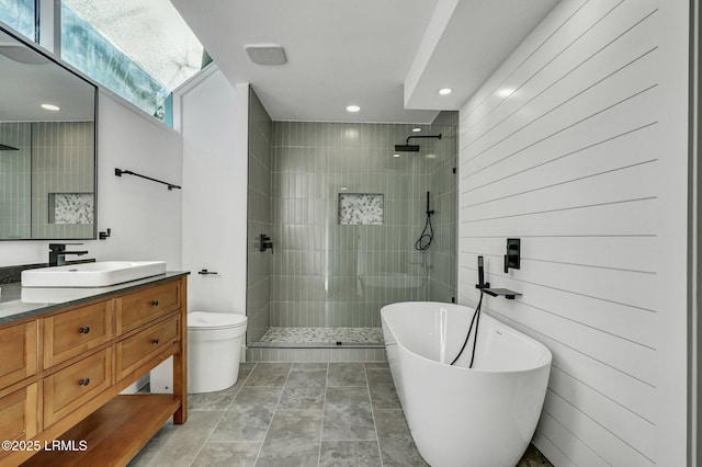 full bathroom featuring toilet, a walk in shower, vanity, and a freestanding tub