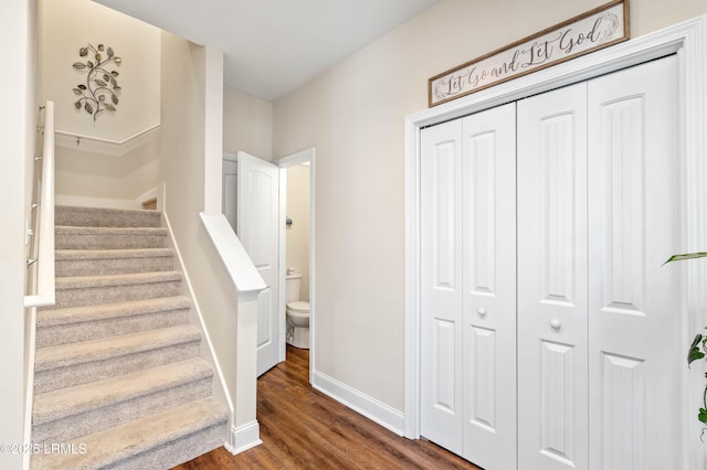 staircase featuring wood finished floors and baseboards