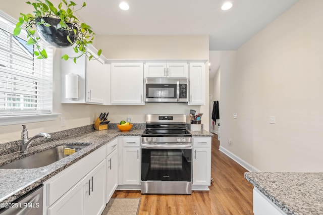 kitchen featuring light wood-style flooring, white cabinetry, stainless steel appliances, and a sink