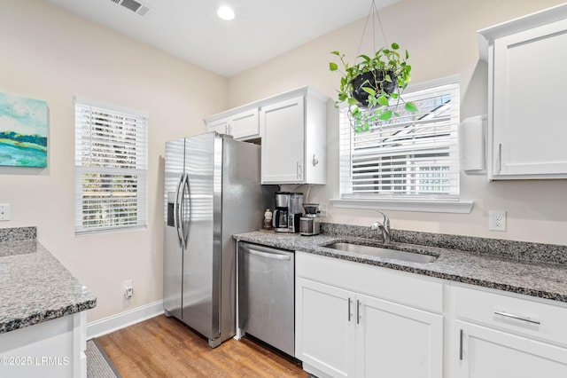 kitchen with a sink, white cabinets, a wealth of natural light, and stainless steel appliances