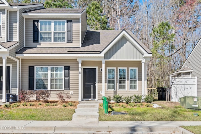 view of front of house featuring board and batten siding, a front yard, roof with shingles, and fence