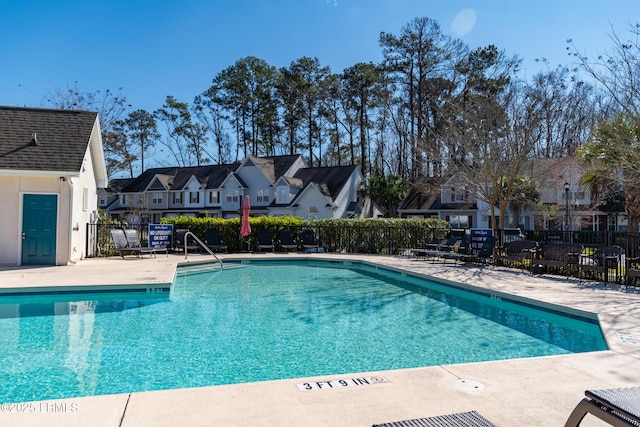 pool with a patio area, a residential view, and fence