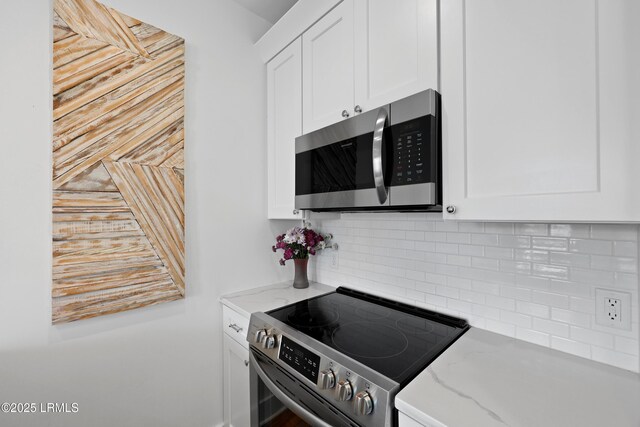 142 President St, Charleston, SC 29403 - kitchen featuring appliances with stainless steel finishes, white cabinetry, light stone counters, and tasteful backsplash