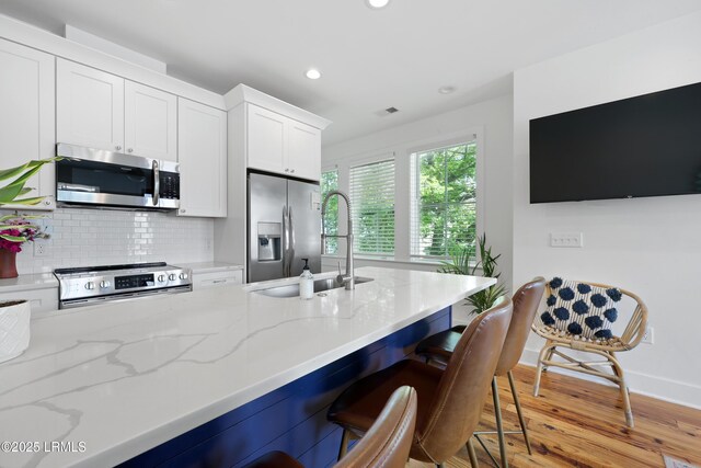 142 President St, Charleston, SC 29403 - kitchen featuring stainless steel appliances, light stone counters, white cabinets, a sink, and recessed lighting