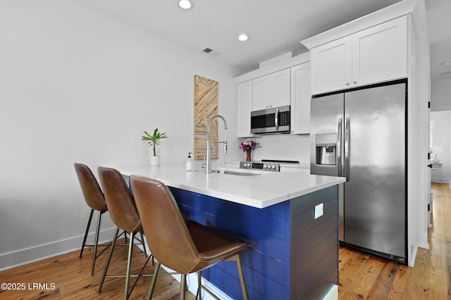 142 President St, Charleston, SC 29403 - kitchen with appliances with stainless steel finishes, a sink, recessed lighting, a kitchen breakfast bar, and white cabinetry