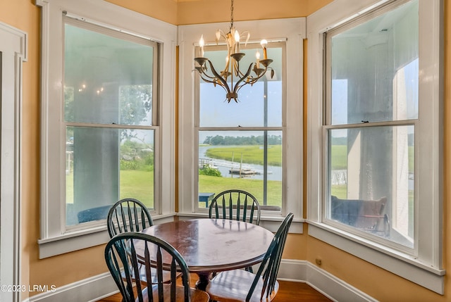 sunroom featuring a water view and a notable chandelier