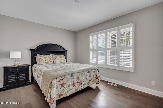 bedroom with visible vents, baseboards, and wood finished floors