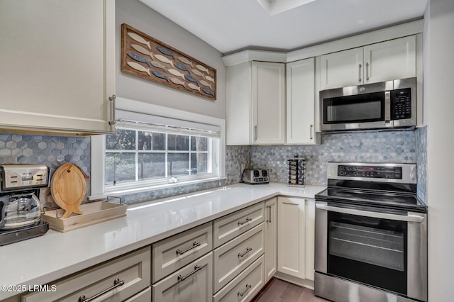 kitchen featuring tasteful backsplash, white cabinetry, stainless steel appliances, and light countertops