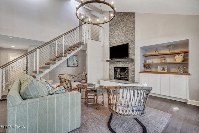 living room featuring wood finished floors, a fireplace, stairs, a towering ceiling, and a notable chandelier