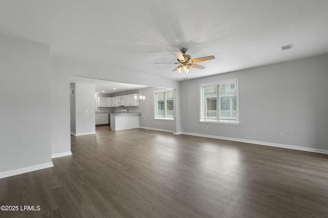 269 Ceasar Pl, Hilton Head Island, SC 29926 - unfurnished living room featuring ceiling fan, a chandelier, baseboards, and dark wood-type flooring