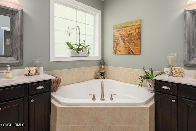 bathroom featuring vanity, a healthy amount of sunlight, and a relaxing tiled tub