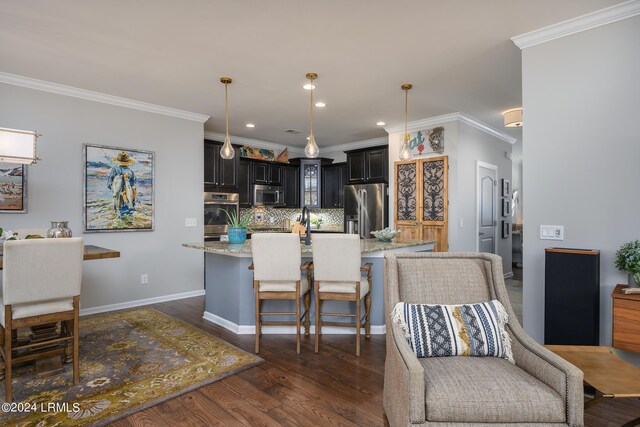 kitchen featuring light stone countertops, appliances with stainless steel finishes, a kitchen island with sink, and decorative backsplash