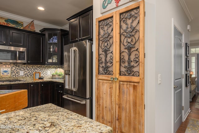 kitchen featuring tasteful backsplash, appliances with stainless steel finishes, crown molding, and light stone countertops